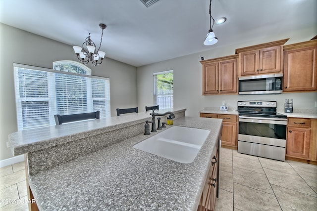 kitchen with hanging light fixtures, brown cabinetry, stainless steel appliances, and a sink