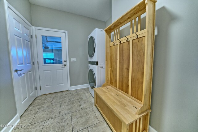 mudroom with stacked washing maching and dryer and light tile patterned floors