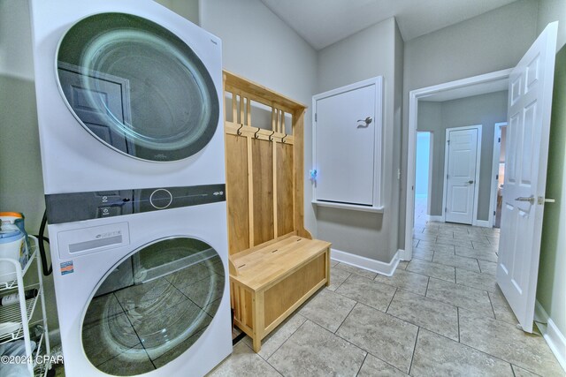 laundry room with stacked washer and clothes dryer and light tile patterned floors