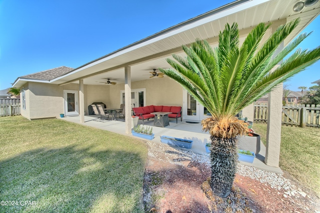 rear view of house with ceiling fan, fence, an outdoor living space, and stucco siding