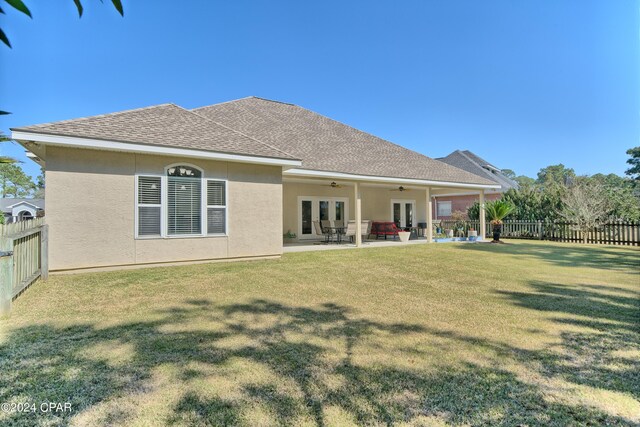 rear view of house featuring ceiling fan, a patio, and a yard