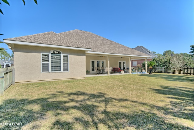 rear view of property featuring a lawn, a patio, a ceiling fan, a fenced backyard, and french doors