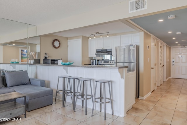 kitchen featuring a breakfast bar area, kitchen peninsula, white cabinets, and light stone counters