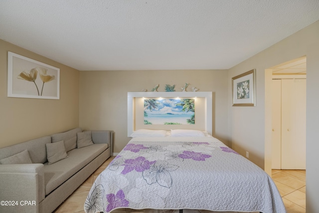 bedroom featuring light tile patterned floors, a textured ceiling, and a closet