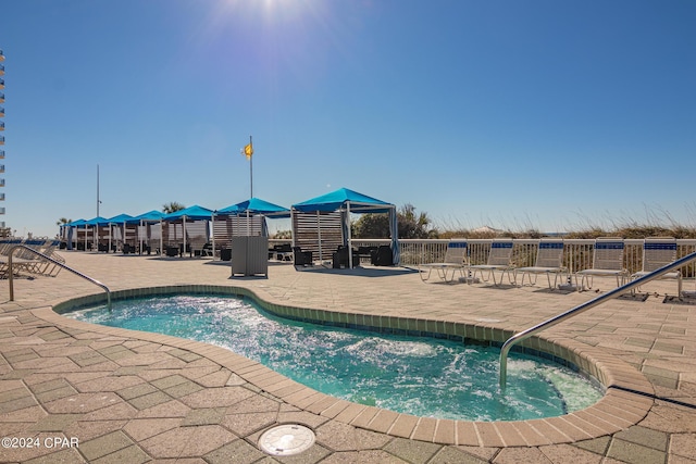 view of swimming pool featuring a patio area and a hot tub