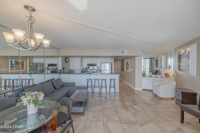 living room with a textured ceiling, a chandelier, and light tile patterned floors