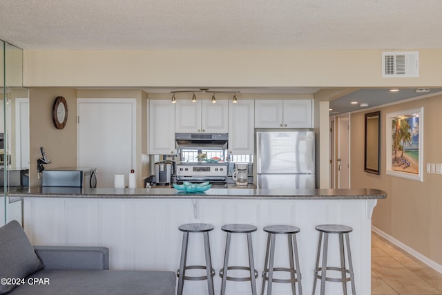 kitchen with appliances with stainless steel finishes, light tile patterned flooring, a kitchen bar, and white cabinets