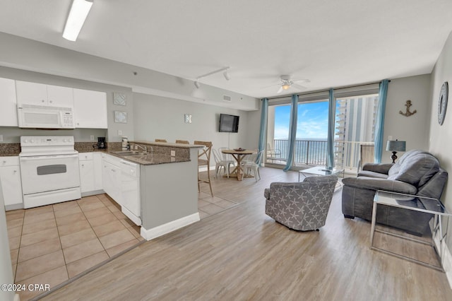 kitchen featuring white appliances, light hardwood / wood-style flooring, expansive windows, white cabinets, and kitchen peninsula