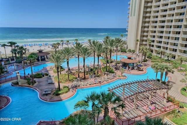 view of swimming pool with a water view, a beach view, and a pergola