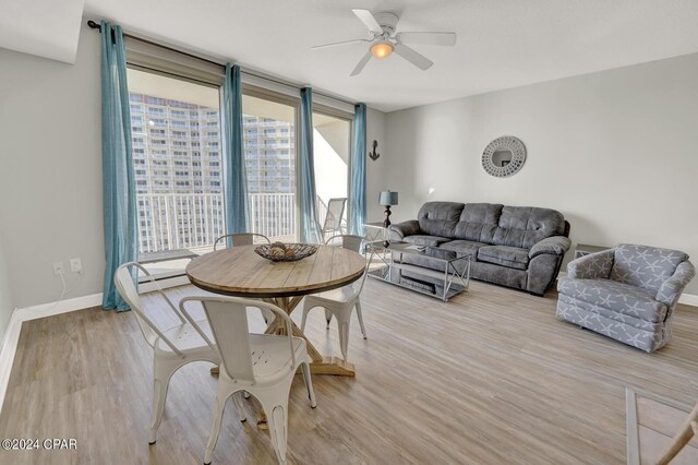 living room with expansive windows, ceiling fan, and light wood-type flooring