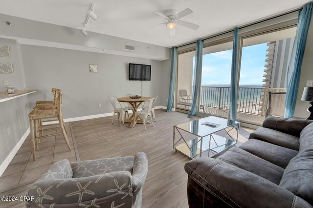 living room featuring a water view, light hardwood / wood-style floors, ceiling fan, and track lighting