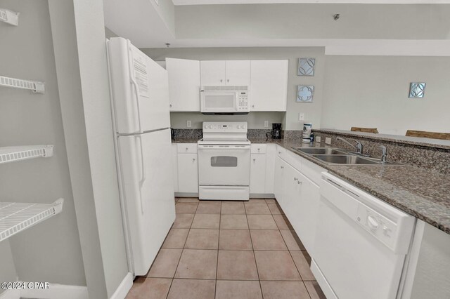 kitchen featuring light tile flooring, stone counters, white appliances, white cabinetry, and sink