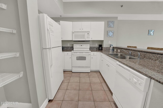 kitchen featuring light tile patterned flooring, white cabinetry, sink, dark stone countertops, and white appliances