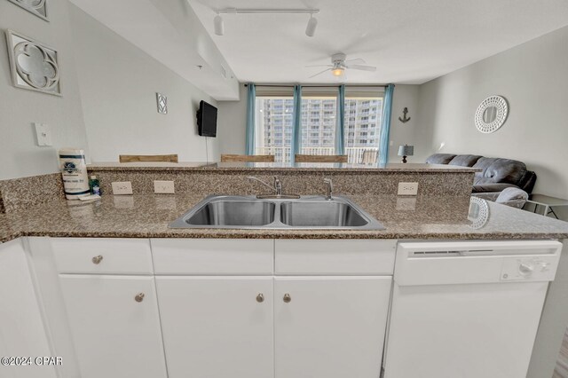 kitchen featuring stone counters, ceiling fan, sink, rail lighting, and dishwasher