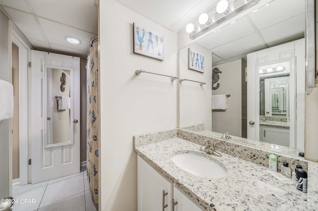 bathroom with vanity with extensive cabinet space, tile flooring, and a paneled ceiling