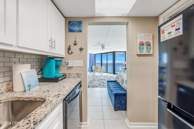 kitchen with light tile floors, backsplash, white cabinetry, dishwashing machine, and black refrigerator