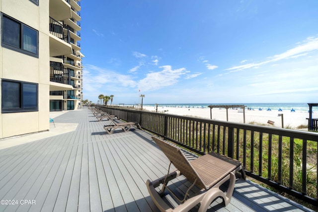 wooden terrace featuring a water view and a view of the beach