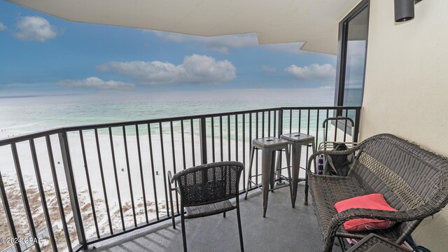 balcony featuring a view of the beach and a water view