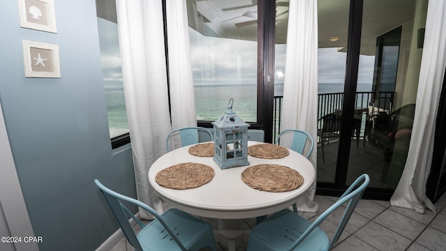 dining space featuring tile patterned flooring, a water view, a healthy amount of sunlight, and ceiling fan