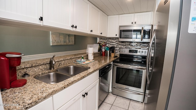 kitchen featuring sink, white cabinetry, light stone counters, appliances with stainless steel finishes, and decorative backsplash