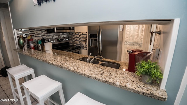 kitchen with appliances with stainless steel finishes, tasteful backsplash, sink, light stone counters, and kitchen peninsula