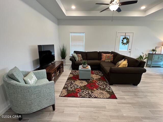 living room with ceiling fan, a tray ceiling, and recessed lighting