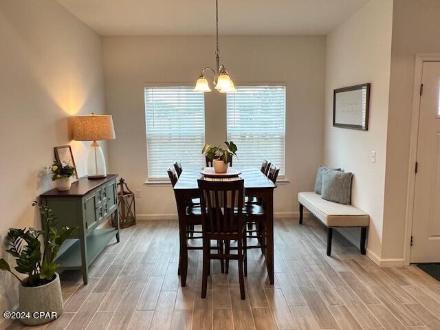 dining area featuring light wood-type flooring, baseboards, and an inviting chandelier