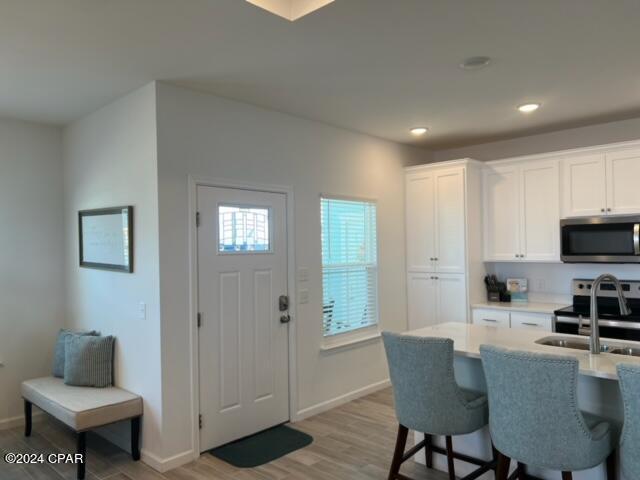 kitchen featuring stainless steel appliances, light countertops, light wood-style flooring, white cabinets, and a sink