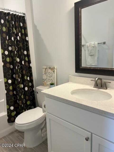 full bath with wood tiled floor, shower / tub combo with curtain, vanity, and toilet