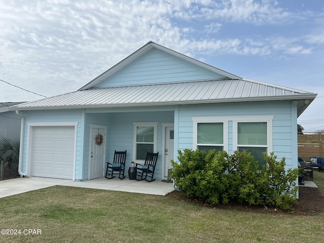 view of front facade with a garage, metal roof, a front lawn, and a porch