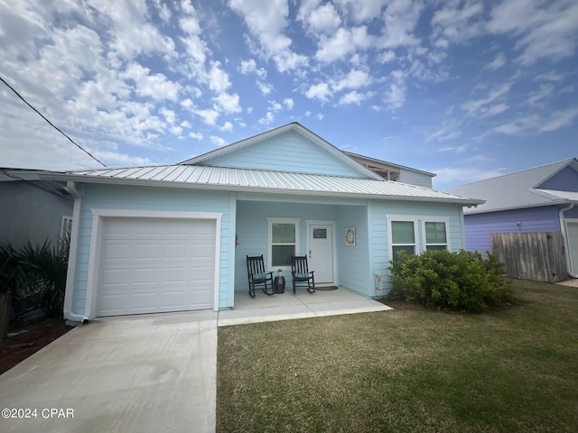 view of front facade featuring metal roof, a porch, an attached garage, fence, and a front lawn