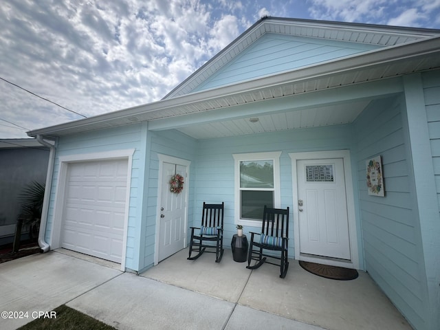 view of exterior entry featuring a garage and covered porch