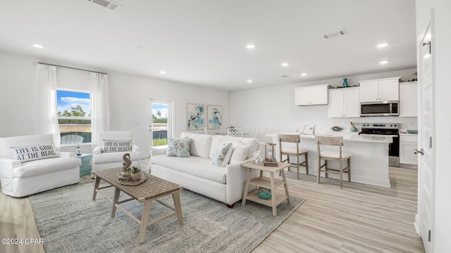 living area with light wood-style flooring, recessed lighting, and visible vents