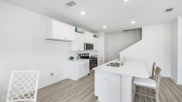 kitchen with a sink, stainless steel appliances, visible vents, and light wood finished floors