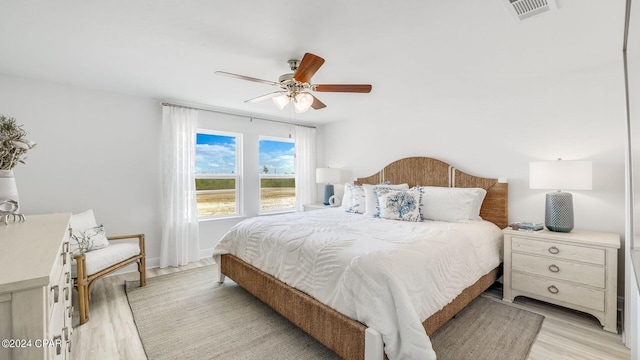 bedroom with baseboards, visible vents, a ceiling fan, and light wood-style floors