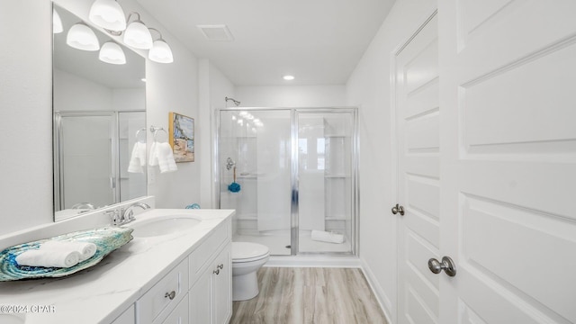 full bathroom featuring vanity, wood finished floors, visible vents, a shower stall, and toilet