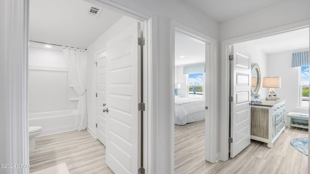 bathroom with hardwood / wood-style floors, toilet, and shower / bathtub combination with curtain