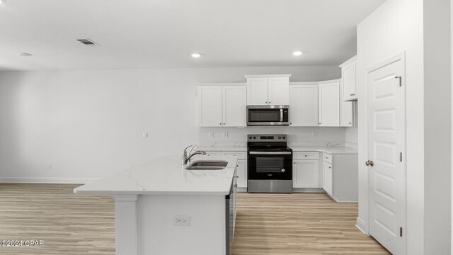 kitchen with light hardwood / wood-style flooring, sink, a center island with sink, and white cabinets