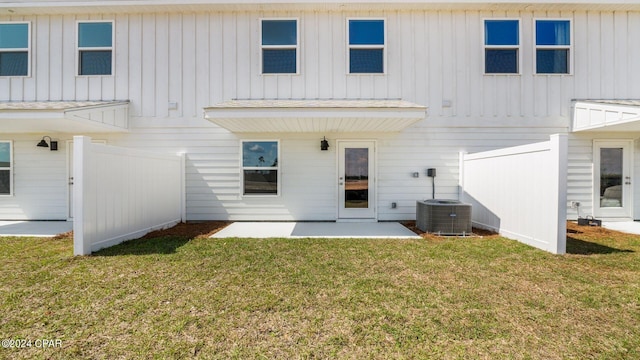 rear view of house with a patio, central AC unit, fence, a yard, and board and batten siding