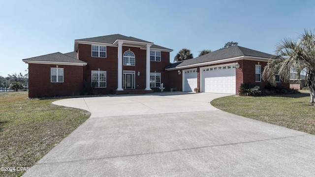 greek revival house with a garage, a front yard, concrete driveway, and brick siding