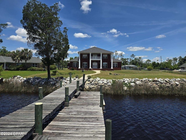 view of dock featuring a lawn, a balcony, and a water view