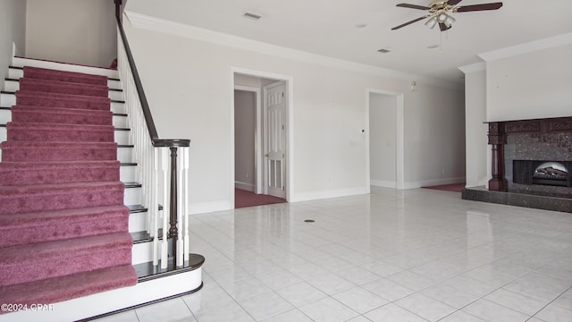 unfurnished living room with crown molding, a ceiling fan, a high end fireplace, baseboards, and stairs