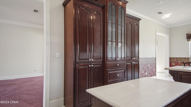 kitchen with visible vents, light countertops, ornamental molding, carpet, and glass insert cabinets