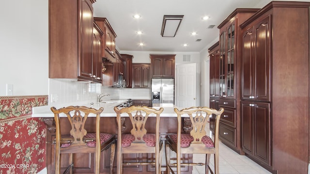 kitchen featuring light tile patterned floors, a peninsula, light countertops, backsplash, and stainless steel fridge with ice dispenser