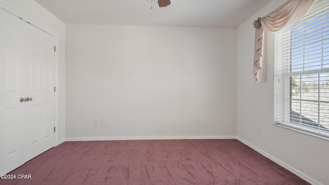 carpeted spare room with ceiling fan and baseboards