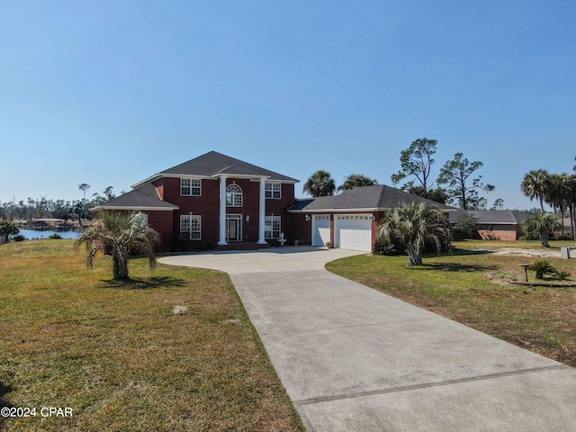 neoclassical home with a garage, a water view, driveway, and a front lawn