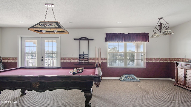 recreation room featuring a wainscoted wall, carpet flooring, a textured ceiling, and french doors