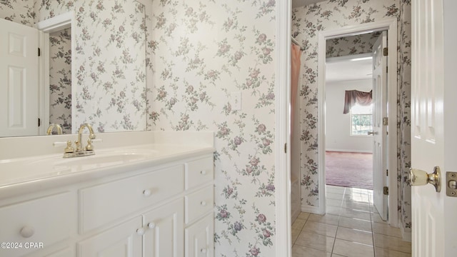 bathroom with wallpapered walls, tile patterned flooring, baseboards, and vanity