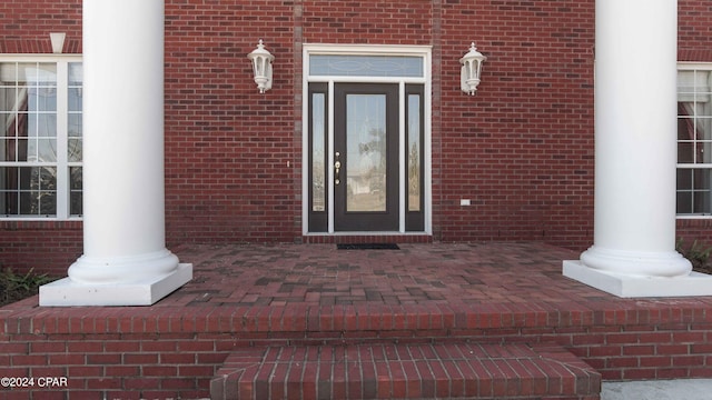 entrance to property featuring brick siding and a patio area