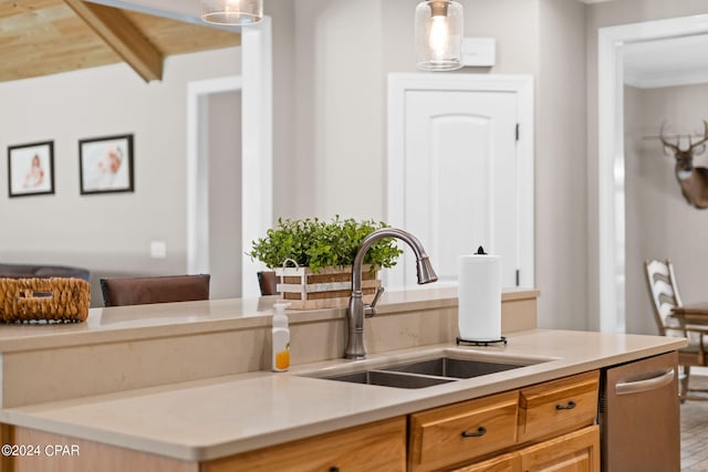 kitchen featuring hanging light fixtures, dishwasher, sink, and beam ceiling